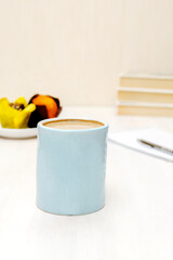 blue espresso coffee cup,latte with milk, fresh baked cakes sweet dessert on plate kitchen table against books, utensils dishware. morning french home breakfast, copy space,mock up.