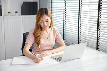 businesswoman using laptop computer and writing on notebook in the office