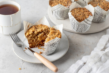 Morning breakfast oatmeal muffins in white paper cups with cup of tea white textured background - Powered by Adobe