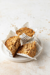 Morning breakfast cutted oatmeal muffins in white paper cups on beige textured background, close up copy space