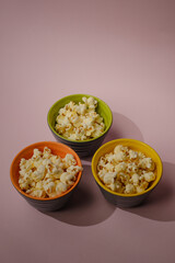 Popcorn looked down from above on a yellow background. The bowl of popcorn was lying flat. Top View.