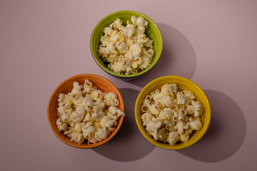 Popcorn looked down from above on a yellow background. The bowl of popcorn was lying flat. Top View.