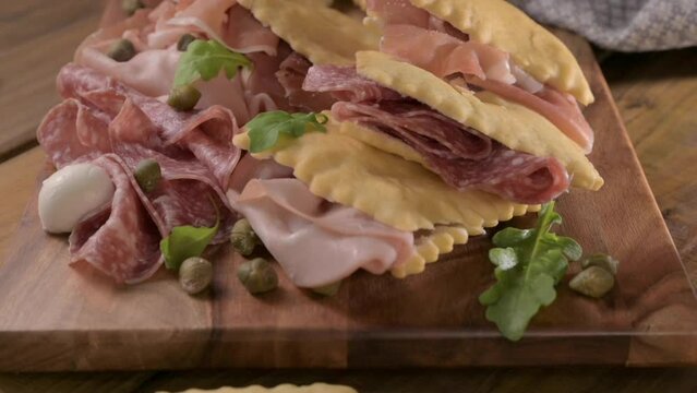 Crescentina. Food of Emilia Romagna region, deep fried bread gnocco fritto or crescentina. Starter or aperitif in Italy. Creshantina with prosciutto crudo, mortadella, Milanese salami, capers, cheese 