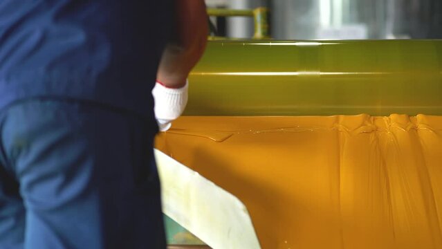 Someone taking sample from freshly produced yellow color at factory