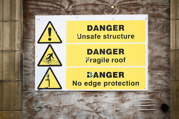 Unstable building keep out dangerous sign on fence at building construction site