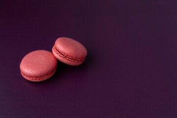 Two pink macaroons on dark purple background