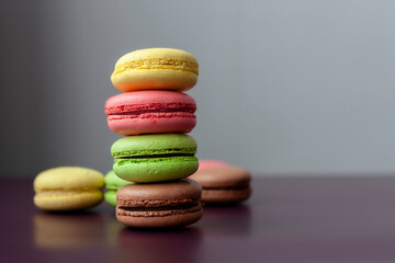 Pile of multi color macaroon or macaron on dark purple background close up