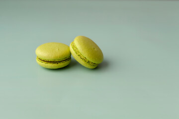 Two green macaroons on turquoise background close up copy space