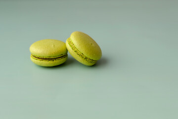 Two green macaroons on turquoise background close up copy space