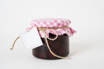 Jar of homemade strawberry jam with empty label isolated on white background.