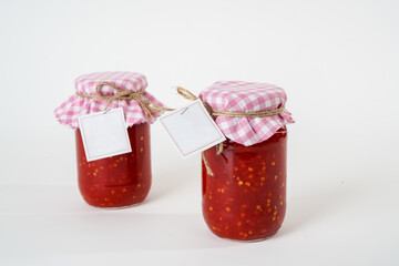 Two canned homemade chili tomato sauce jars with empty labels isolated on white background.