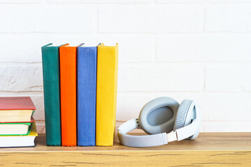Fototapeta na wymiar Audio books concept. Wireless Headphones and color books at wooden table white background.