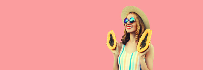 Summer portrait of happy smiling young woman with papaya looking away wearing straw hat, sunglasses...