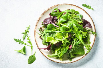 Green salad, fresh leaves in white plate. Top view.