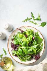 Green salad, fresh leaves in white plate. Top view.