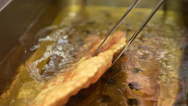 Pasties cheburek with meat fried in sunflower oil, deep fry. Crimean Tatar fast food, traditional food. Dough in a pan with hot oil