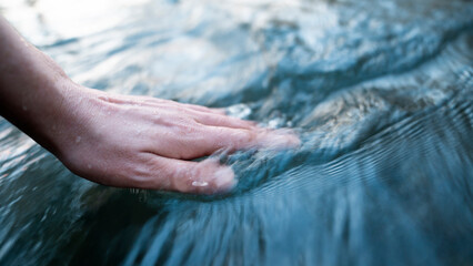 A female hand touching the river water - 575716326