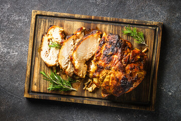 Roasted pork, baked ham on serving board at black.
