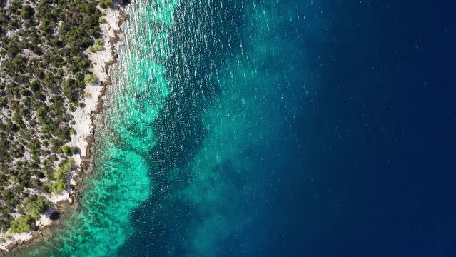 Flying over the turquoise Adriatic Sea waves drone video with lonely yacht near the rocky coast. Aerial coastal top view 4K footage.