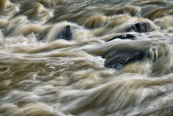 Detail of wild muddy river with rapids