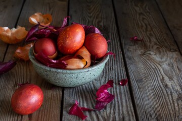 Boiled eggs dyed with onion peel in a bowl on a wooden background. Traditional Easter concept.