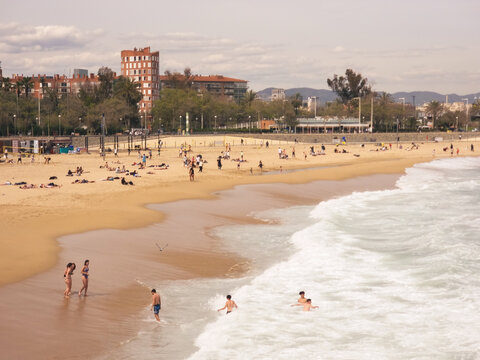 Panoramic view of the beach called Nova Icaria, one of the urban beaches of Barcelona, where we can see people having fun, enjoying the sun and the sea.