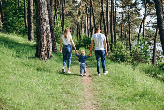 Family photo session on the street on a warm sunny day in a coniferous forest in spring