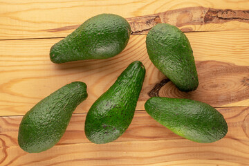 Several juicy avocados on a wooden table, macro, top view.
