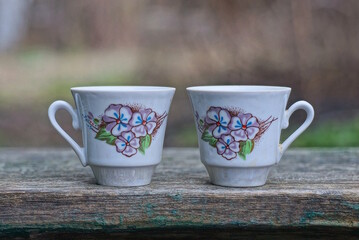 two small white coffee ceramic cups with a color pattern stand on a gray table