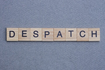 text the word despatch from brown wooden small letters with black font on an gray table