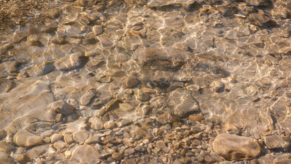 Piedras en el fondo y superficie del agua de un arroyo