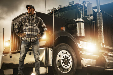 Professional Truck Driver Proudly Standing in Front of His Heavy Duty Vehicle
