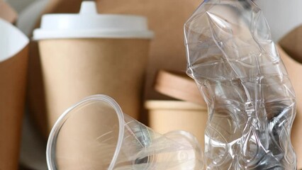 A plastic bottle and a disposable cup on the background of eco-friendly tableware and paper packaging. Zero waste and no plastic concept