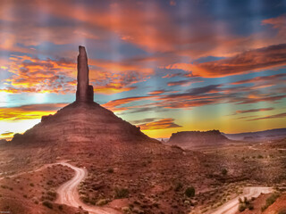  Multicolored Sunset behind a spire in valley of the gods with a twisting road in the foreground....