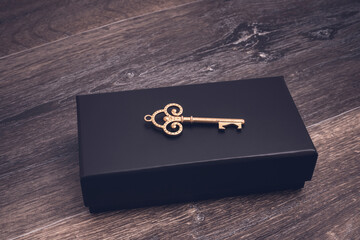 Vintage key on a black box on a wooden background