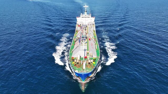 Aerial drone loop video of industrial liquified LPG gas tanker cruising near gas terminal