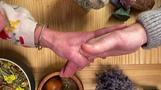 Table top view female male hands while divination palmistry session. Witch reading fortune lines on male palm hand. Fortune teller predicting fate to customer indoors. Mystic medium seance. Chiromancy