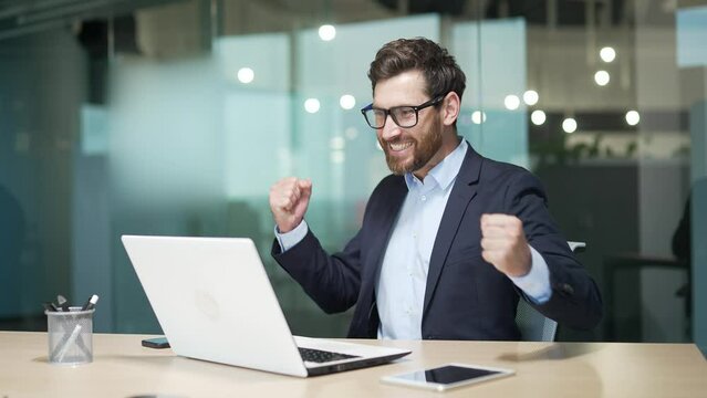 Overjoyed business man freelancer extremely happy after read email message on laptop at modern workplace Excited mature entrepreneur look at screen and pleased rejoices received great news on computer