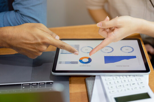 close up group of businesspeople talk and discuss about company's profit summary report on dashboard digital tablet to achieve and set target monthly for 