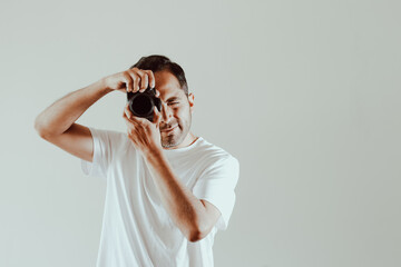 Male photographer taking a picture on a light background. Concept of technology, professions, lifestyles and arts.