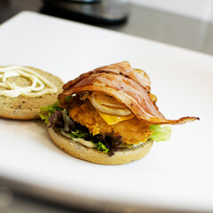 Burger with chicken and bacon on the kitchen table in the restaurant