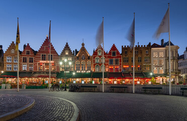 Obraz premium Colorful houses on the main square in the city center of Bruges with restaurants during evening