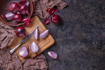 Top view of ripe red onion bulbs and chopped onion on a stone surface, flat lay with copy space for...