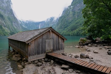 View of the wooden hut and pier at Obersee, Berchtesgadener, Germany. Obersee and Bercgtesgadener Mountains. Schönau am Königssee. 