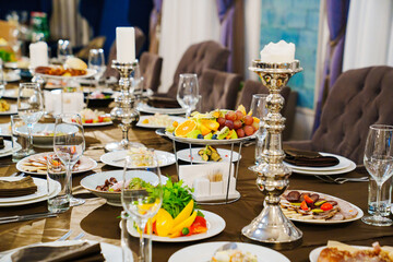 a large festive table with candles, snacks and tableware.