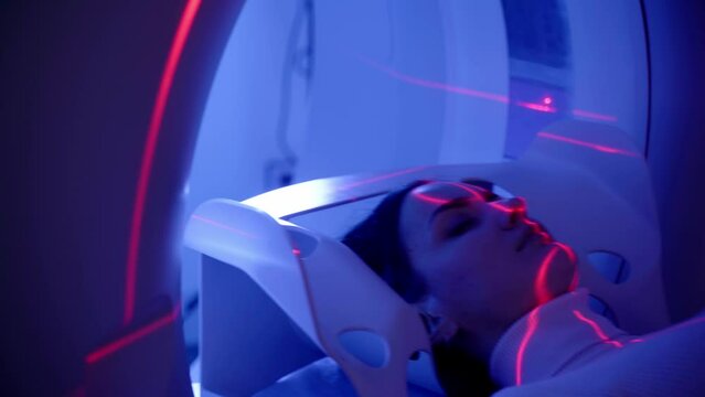 4k video CT x-ray examination of lung cancer with red lines and blue light in medical clinic. Patient girl lies on computed tomography bed and scanning lungs for diagnose lung cancer.