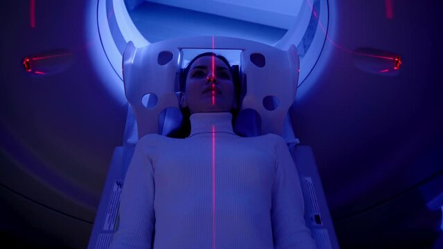 4k video CT x-ray examination of lung cancer with red lines and blue light in medical clinic. Patient girl lies on computed tomography bed and scanning lungs for diagnose lung cancer.