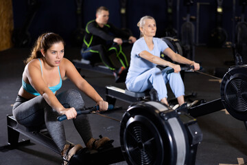 Fototapeta na wymiar Athlete woman works on the rowing simulator in gym