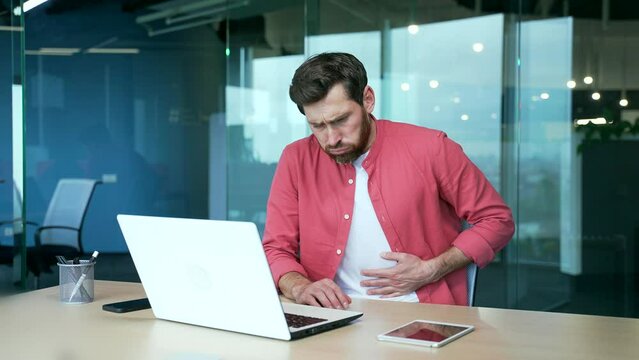 Sick office worker Stomach pain feeling spasms cramps in his stomach during work on laptop, constipation or heartburn acute discomfort indigestion digestive problems sharp ache in abdomen bad feeling