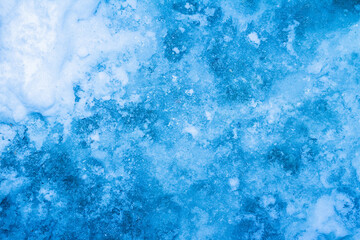 Fototapeta na wymiar Close up photo texture of highlighted blue toned frozen water surface.